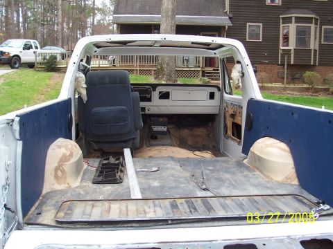1979 Ford Bronco - Dismantled 1979 Ford F-Series truck interior and bed. A white pickup is visible in the background.