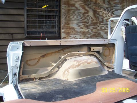 1979 Ford Bronco - The interior of a vehicle's bed is shown, with visible rust and wear on the wheel well.