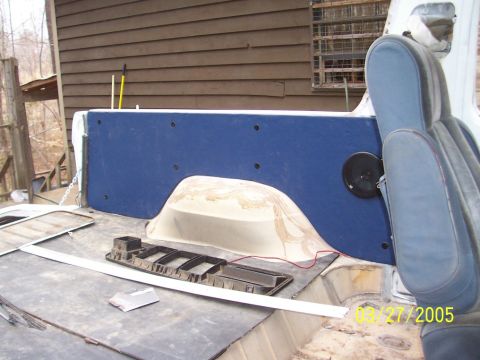 1979 Ford Bronco - The interior of a vehicle shows blue seats and a blue panel with a speaker, with the floor exposed.