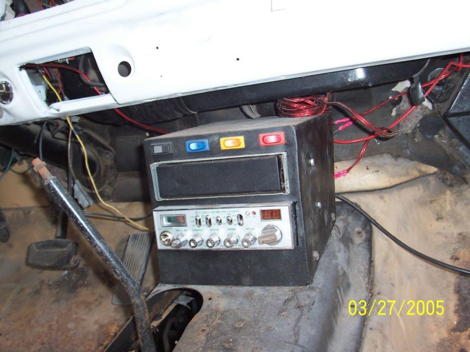 Vehicle interior showing a stacked CB radio and stereo unit mounted under the dashboard, with exposed wiring