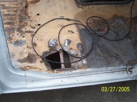 1979 Ford Bronco - The floor of the vehicle shows significant rust damage and a large opening, with electrical wires lying on the surface.