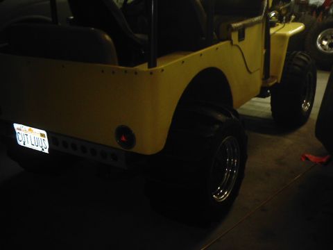1978 Ford Bronco - The rear view of a modified yellow jeep shows off its large off-road tires and a personalized license plate.