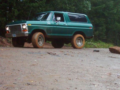 1978 Ford Bronco - This green 1978 Ford Bronco is seen off-road on a dirt path surrounded by trees.