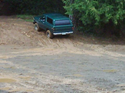1978 Ford Bronco - A 1978 Ford Bronco navigates a muddy, wooded terrain.