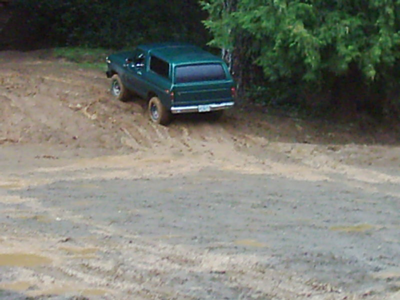 Green 1978 Ford Bronco on a muddy incline, rear view