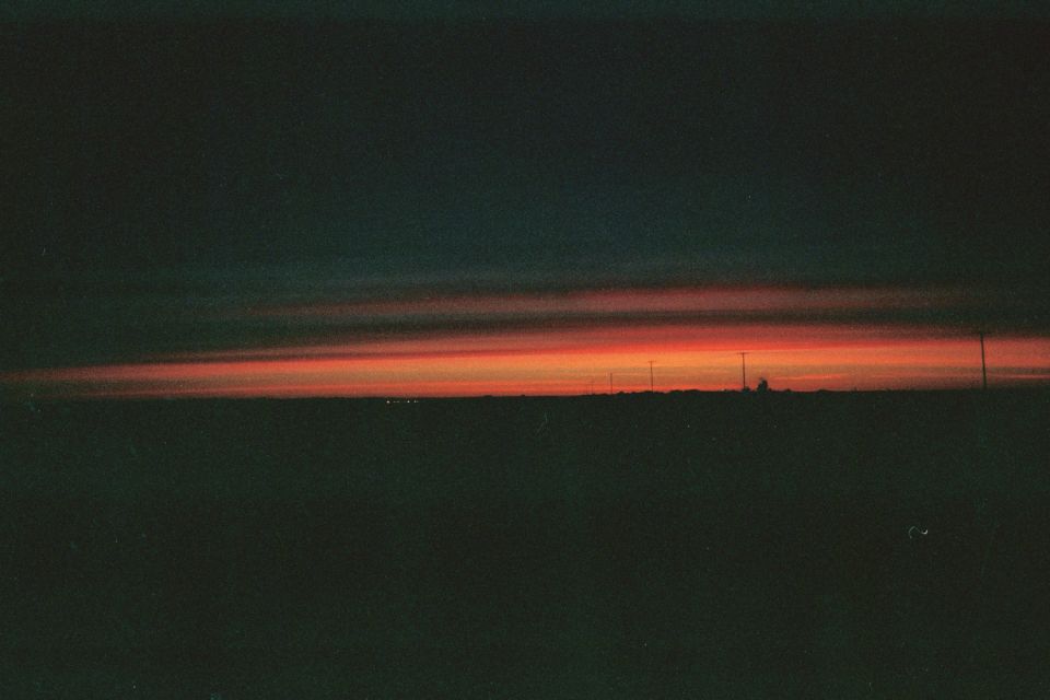Orange and dark sunset over a flat horizon with a faint structure