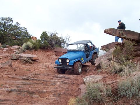 1991 Ford Bronco - A blue Jeep CJ-7 navigates a challenging rocky terrain during an off-road event.