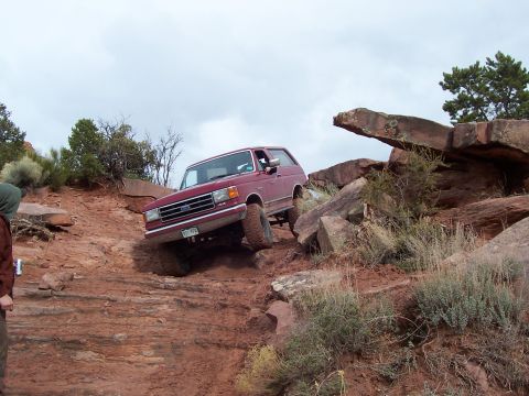 1991 Ford Bronco - A red 1991 Ford Bronco navigates a challenging rocky incline during the Moab Easter Jeep Safari.