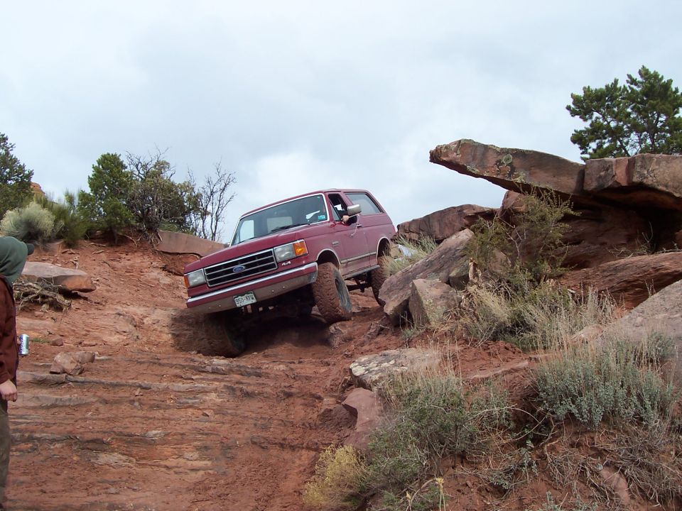 Red 1991 Ford Bronco climbing a rocky trail