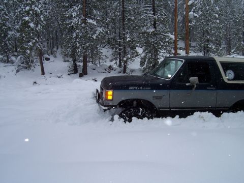 1989 Ford Bronco - A two-tone blue and gray 1987 Ford Bronco is stuck in deep snow in a wooded area.