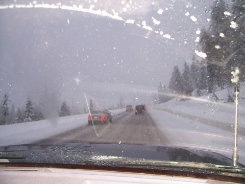 1989 Ford Bronco - View from inside a vehicle driving on a snow-covered road with trees on the side.