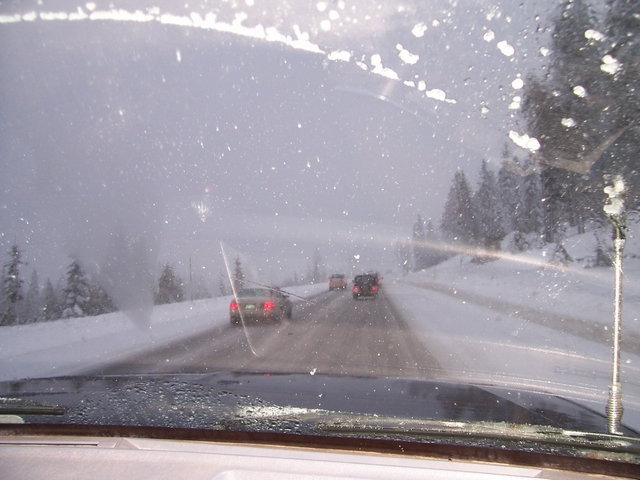 driving on a snowy highway with other cars ahead