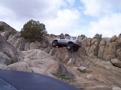 1989 Ford Bronco - A silver Jeep Grand Cherokee navigates a challenging rocky trail during an off-road excursion.