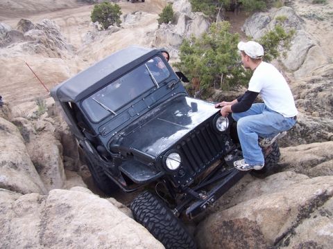 1989 Ford Bronco - Jeep CJ-7 struggling on a steep, rocky incline during an off-road excursion.