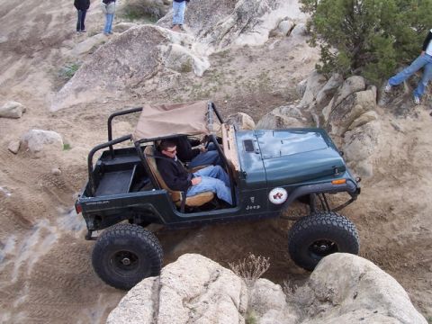 1989 Ford Bronco - A Jeep Wrangler navigates a rocky off-road trail with onlookers observing from above.