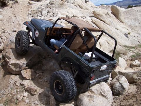 1989 Ford Bronco - Jeep Wrangler tackling a challenging rocky off-road course.