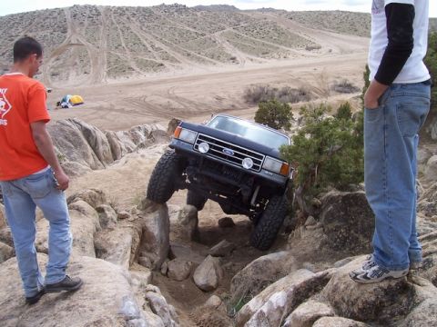 1989 Ford Bronco - A modified Ford Bronco navigates a rocky obstacle course with two spectators observing the action.