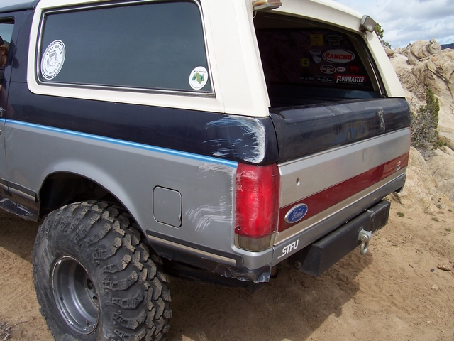 Rear view of a 1989 Ford Bronco with off-road tires and damage on the rear quarter panel