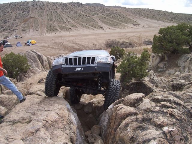 Jeep Grand Cherokee with "STFU" bumper sticker navigating rocky terrain