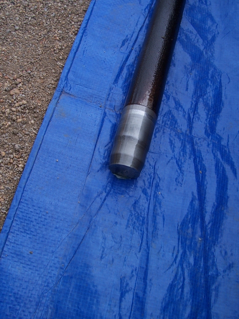 1989 Ford Bronco - A metal shaft rests on a blue tarp, with a silver band visible near the end.