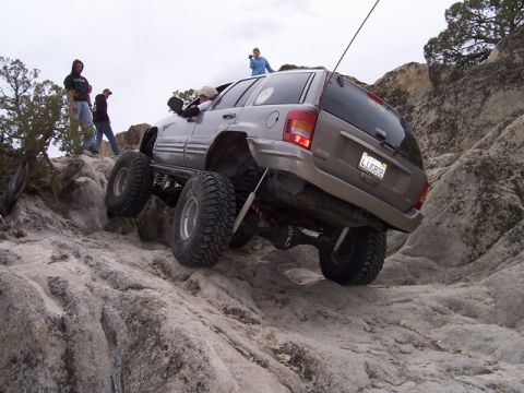 1989 Ford Bronco - This heavily modified Jeep Grand Cherokee navigates a rocky trail with its tires high off the ground.