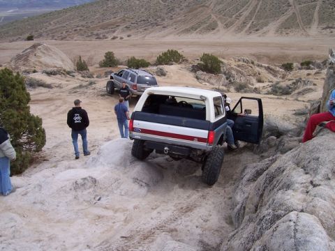 1989 Ford Bronco - Bronco tackling rough off-road trail with friends watching.