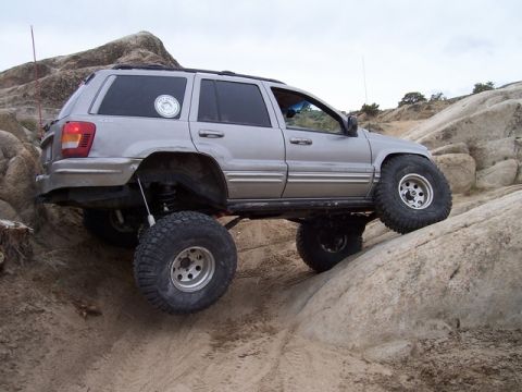 1989 Ford Bronco - This modified Jeep Grand Cherokee is navigating a rocky off-road trail with its tires at steep angles.
