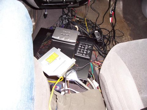 2001 Ford Taurus - The interior of a car is cluttered with various electronic components and wiring, obscuring any clear view of the vehicle's model year.