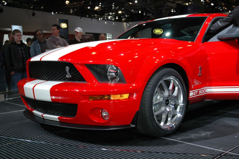 Red 2005 Ford Mustang GT 500 with white stripes, front 3/4 view