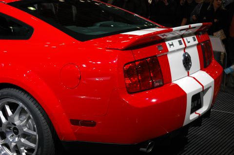 2005 Ford Mustang - Rear view of a red 2007 Ford Mustang Shelby GT500 with iconic white racing stripes.