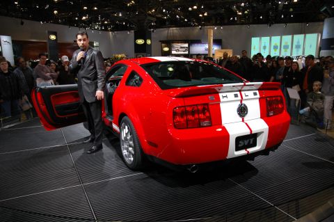 2005 Ford Mustang - A red Ford Mustang Shelby GT500 is displayed with its door open, racing stripes and SVT badging.