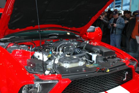 2005 Ford Mustang - The engine bay of a red 2005 Ford Mustang is visible with the hood open, showing the engine and surrounding components.
