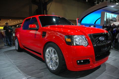 2005 Ford Mustang - A red Ford pickup truck is displayed indoors with its door open, its front end and wheels.