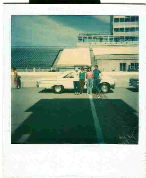 1963 Ford Galaxie - A group poses with a white 1963 Ford Galaxie in front of a grandstand and building.