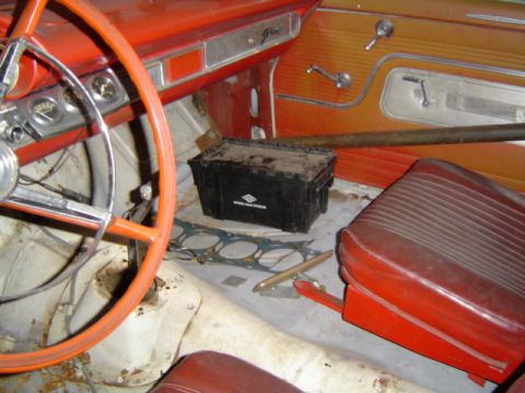 1963 Ford Galaxie - The interior of a classic car shows red seats and door panels, with a toolbox and engine parts on the floor.