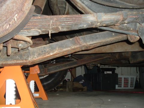 1963 Ford Galaxie - The rear suspension of a 1963 Ford Galaxie, supported by orange jack stands, reveals its restoration needs.