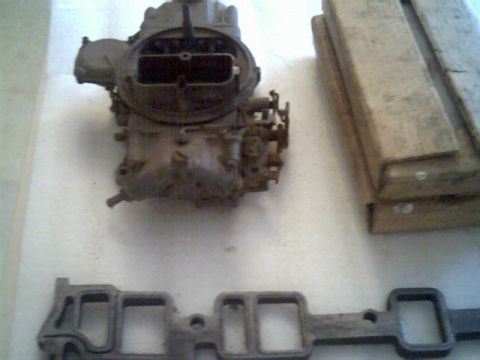 1963 Ford Galaxie - A carburetor and intake manifold are shown, with wooden crates in the background and a Supermotors.net logo.
