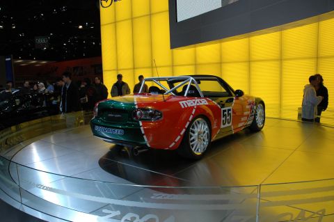 2005 Ford Mustang - A Mazda Miata with a distinctive red and green paint scheme and racing number 55 is displayed on a rotating platform.