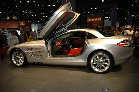 2005 Ford Mustang - Silver Mercedes-Benz SLR McLaren with its distinctive gullwing doors open at an auto show.