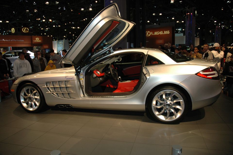 Silver Mercedes-Benz SLR McLaren with gullwing doors open, red interior, on display