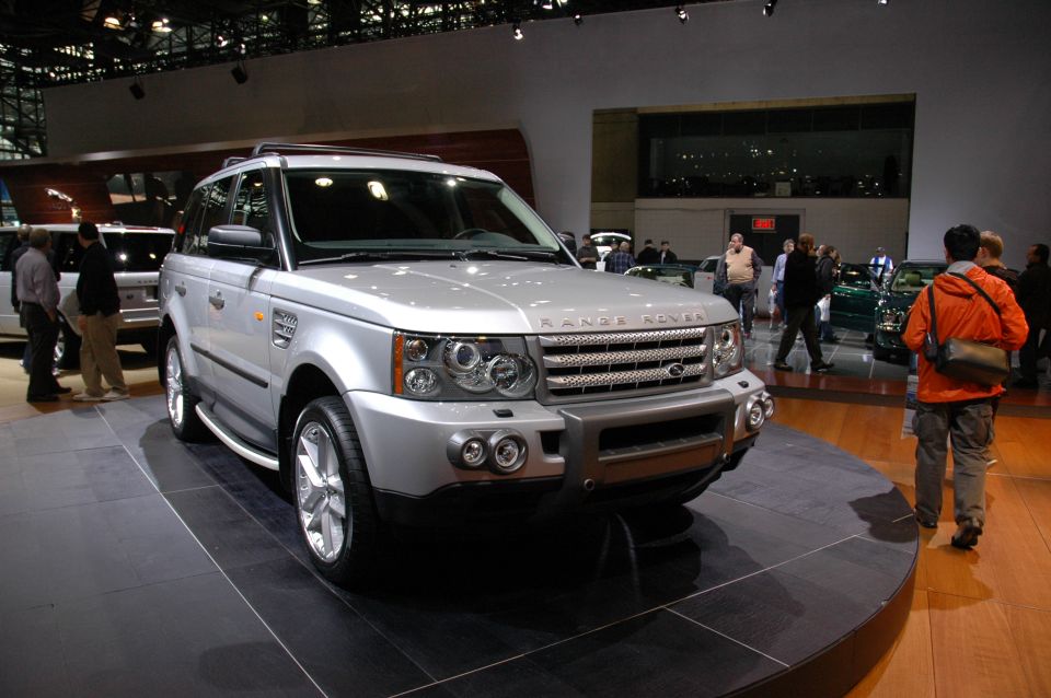 Silver Range Rover on display at an auto show. Text on grille reads 'RANGE ROVER'
