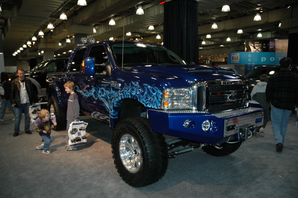 Blue Ford F-250 pickup truck with custom flame graphics and chrome bumper, viewed from a 3/4 front angle