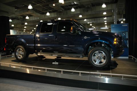 2005 Ford Mustang - A dark blue pickup truck with flame decals is displayed indoors on a raised platform.