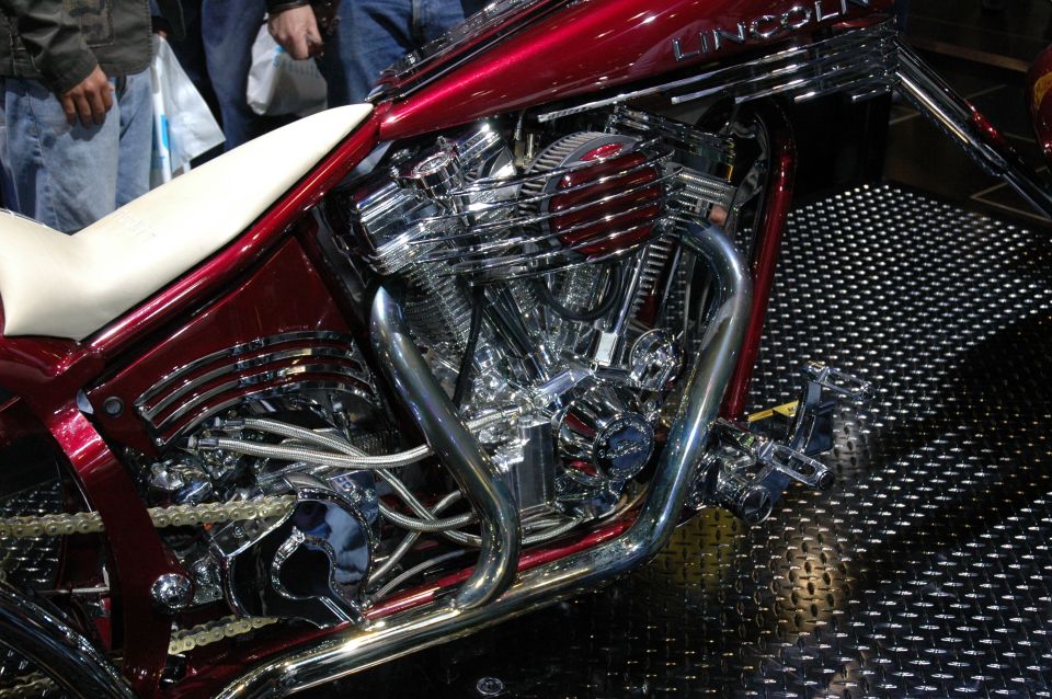 Close-up of a shiny red custom motorcycle engine with chrome accents and a white seat