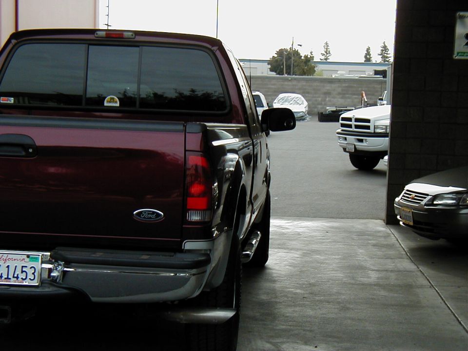 Maroon Ford F-250 Super Duty pickup rear view in a shop lot