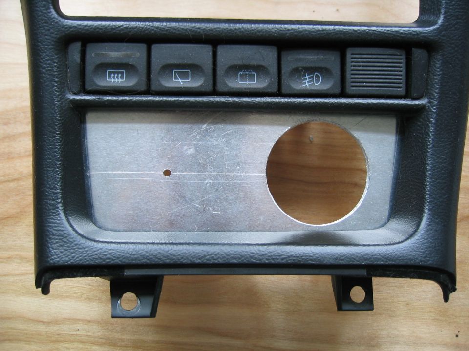Dashboard panel with buttons for rear defrost, fog lights, and a circular cutout