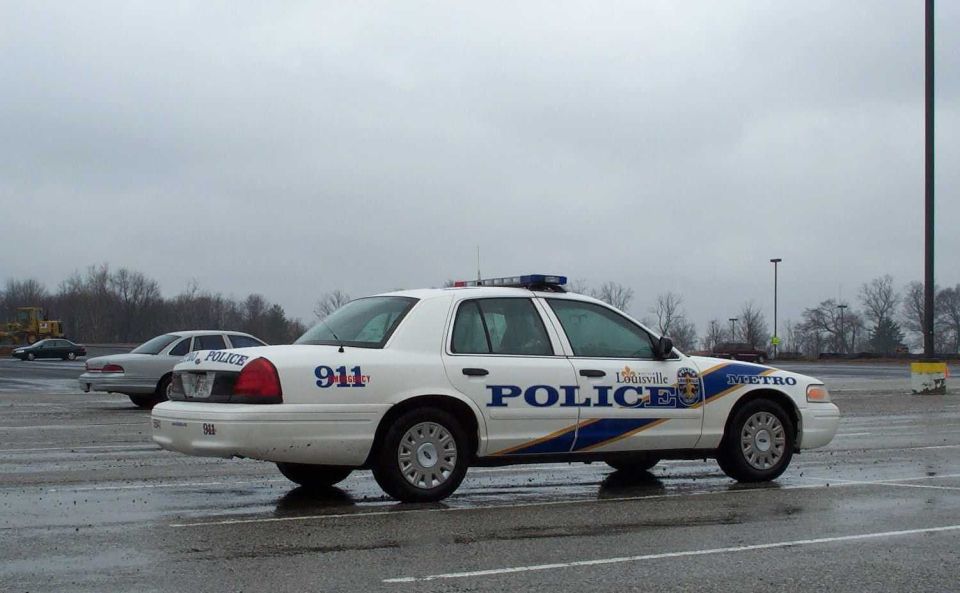 White Louisville Metro Police Crown Victoria sedan in a wet parking lot