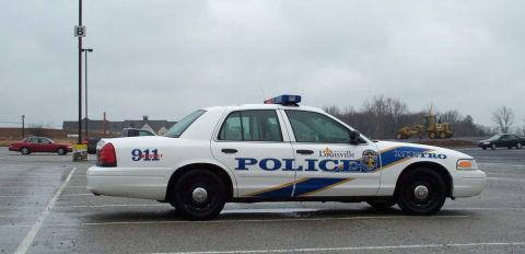1998 Ford Crown Victoria - Side view of a Louisville Metro police car parked in a lot on an overcast day.