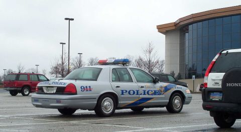 1998 Ford Crown Victoria - A Louisville Metro police car is parked in a lot next to other vehicles under an overcast sky.