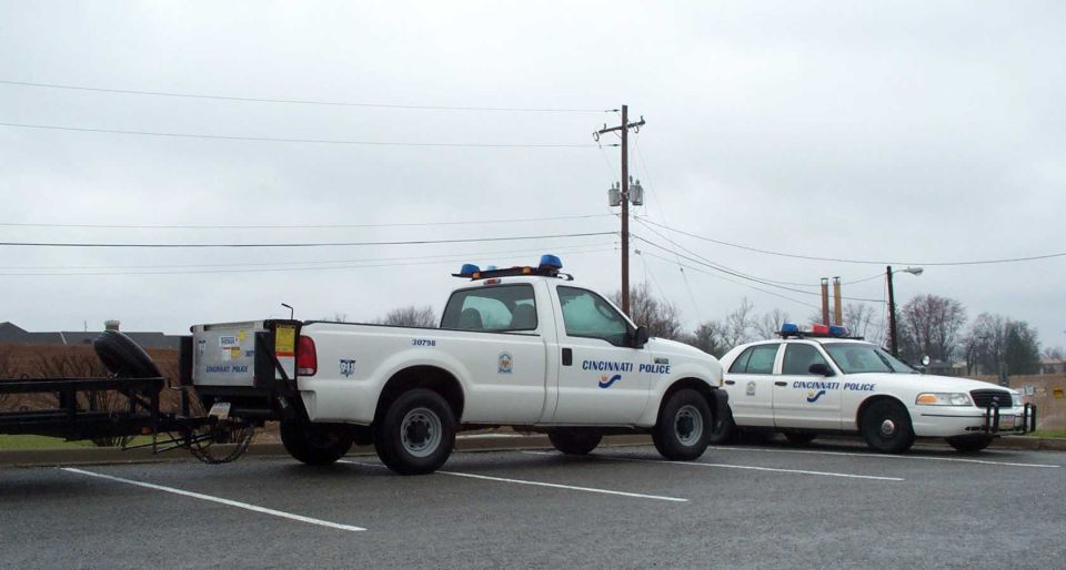 White Cincinnati Police pickup with trailer parked next to a Crown Victoria patrol sedan.